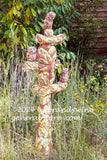 Cactus shape garden sculpture surrounded by tall grass and yellow wildflowers